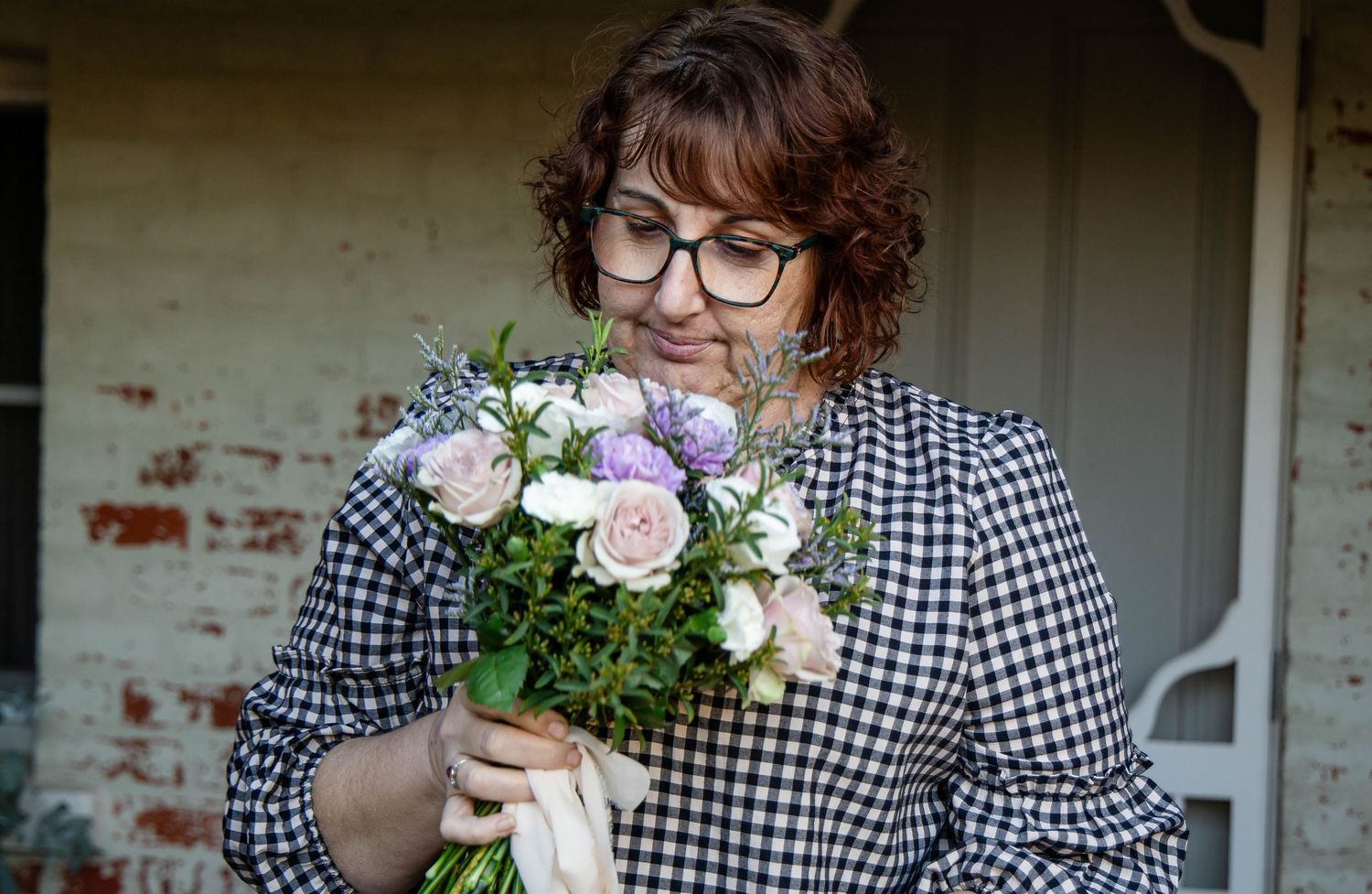 Person in apron holding beautiful bouquet of flowers in floral shop.