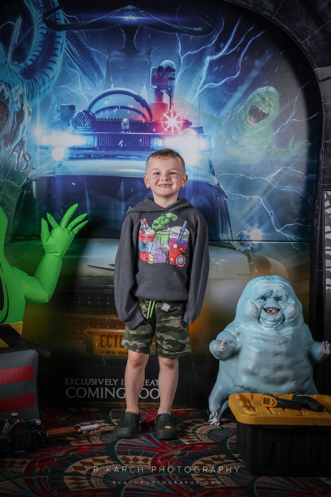 A young boy poses in front of a sci-fi themed backdrop with alien and ghostly decorations.