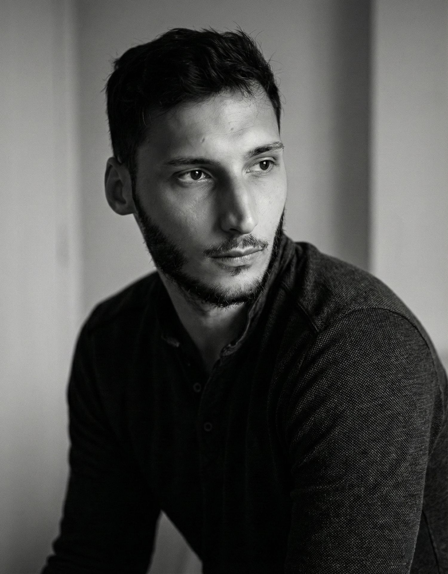 Black and white portrait series showing moody dramatic lighting and shadows against a light background.