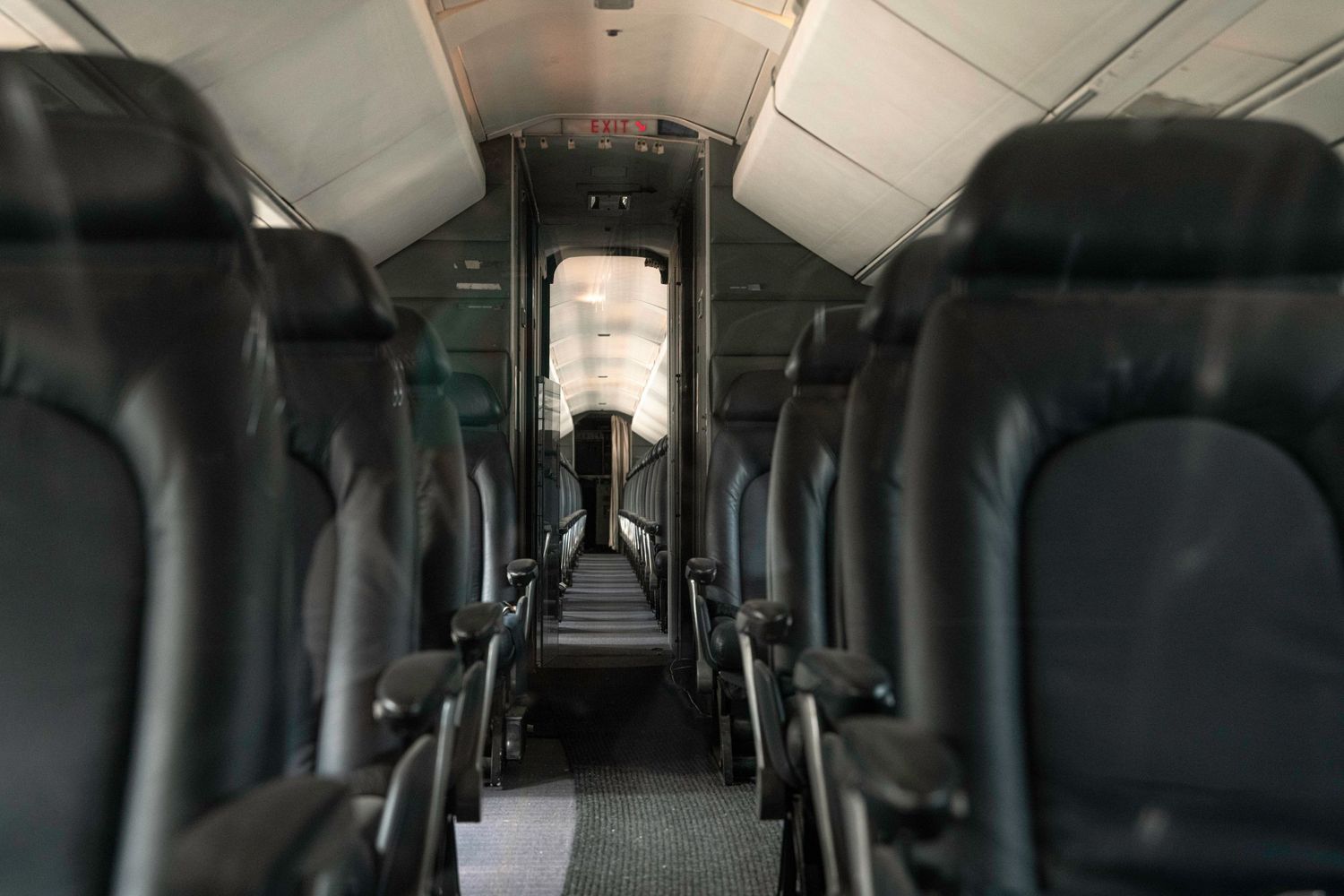 Empty airplane cabin interior showing rows of passenger seats down the aisle.