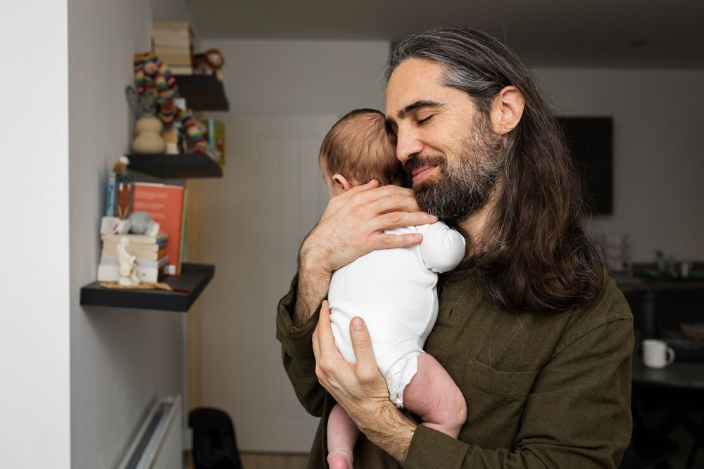 dad holding his baby boy son in his arms with his eyes closed