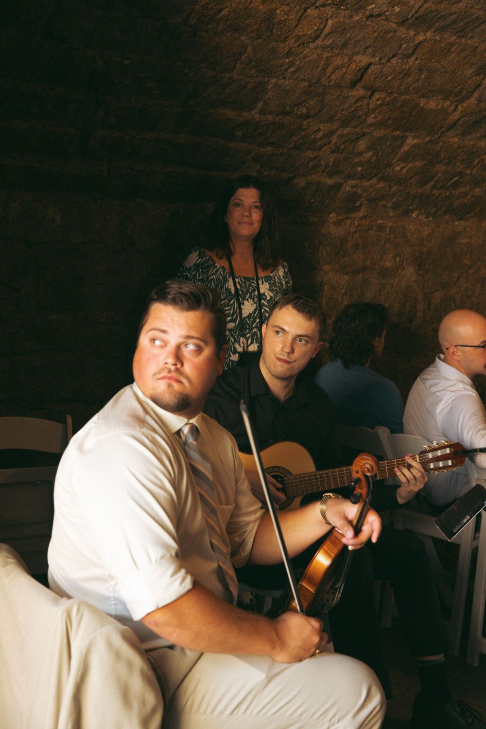 Musicians performing with guitars in atmospheric brick cellar venue.