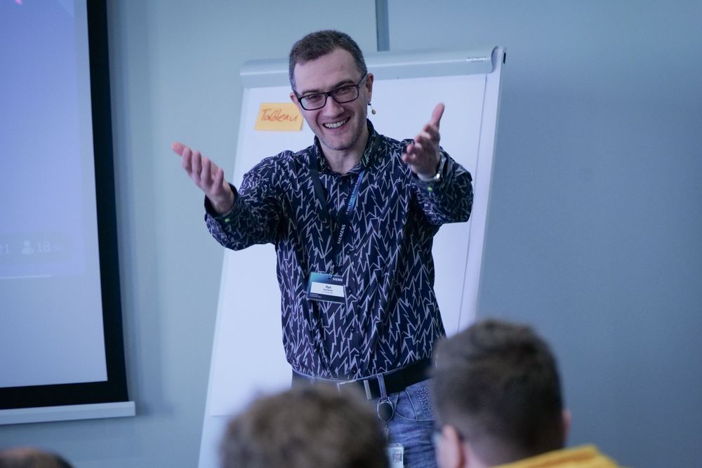 Enthusiastic male speaker presenting to an audience at a Siemens corporate training event.