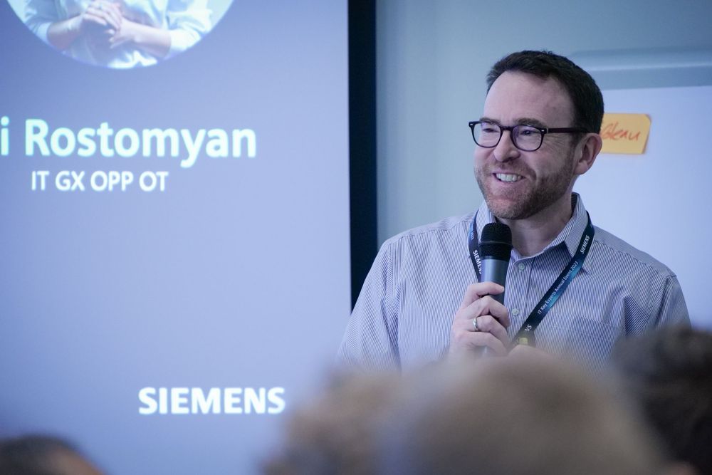 Siemens IT GX OPP OT representative Rostomyan speaks with microphone at corporate conference.