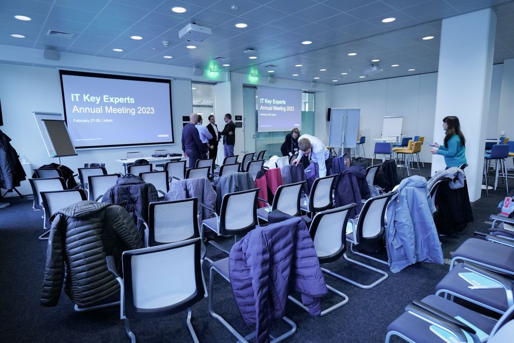 IT Key Experts Annual Meeting 2023 conference room setup with rows of chairs and presentation screen.