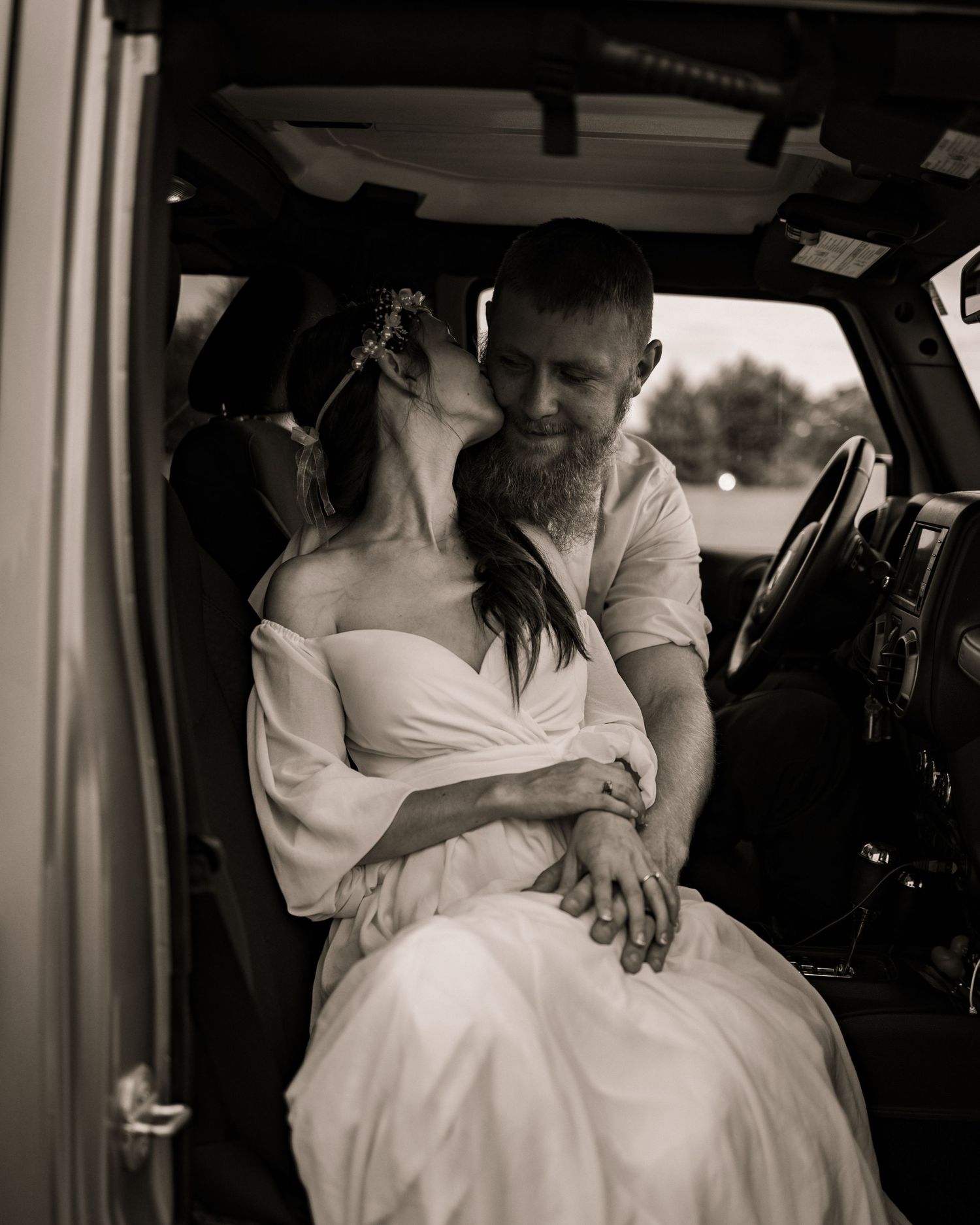 A romantic black and white moment captured inside a vehicle on a wedding day.