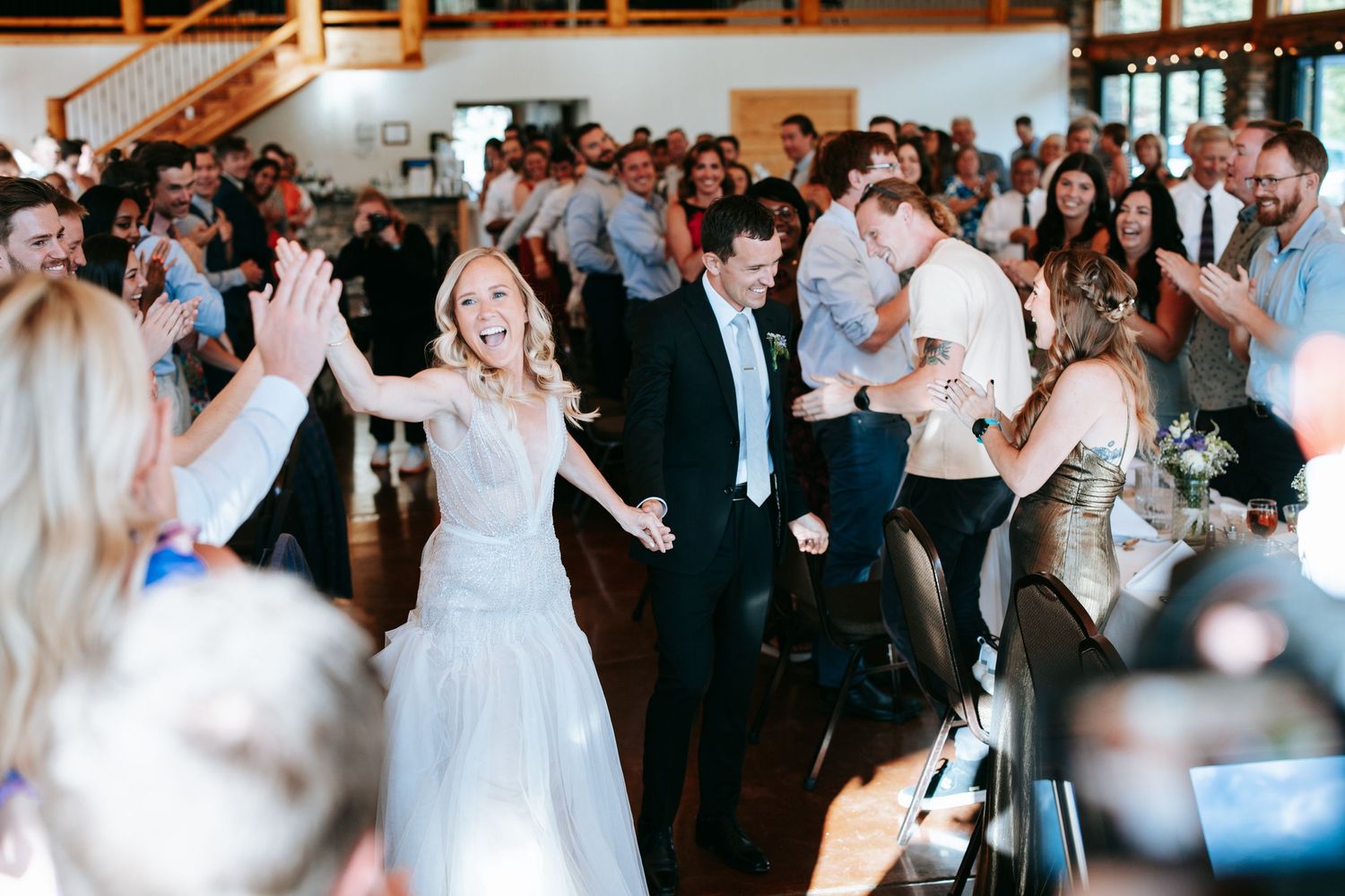 Wedding celebration with guests dancing and cheering in a rustic venue.