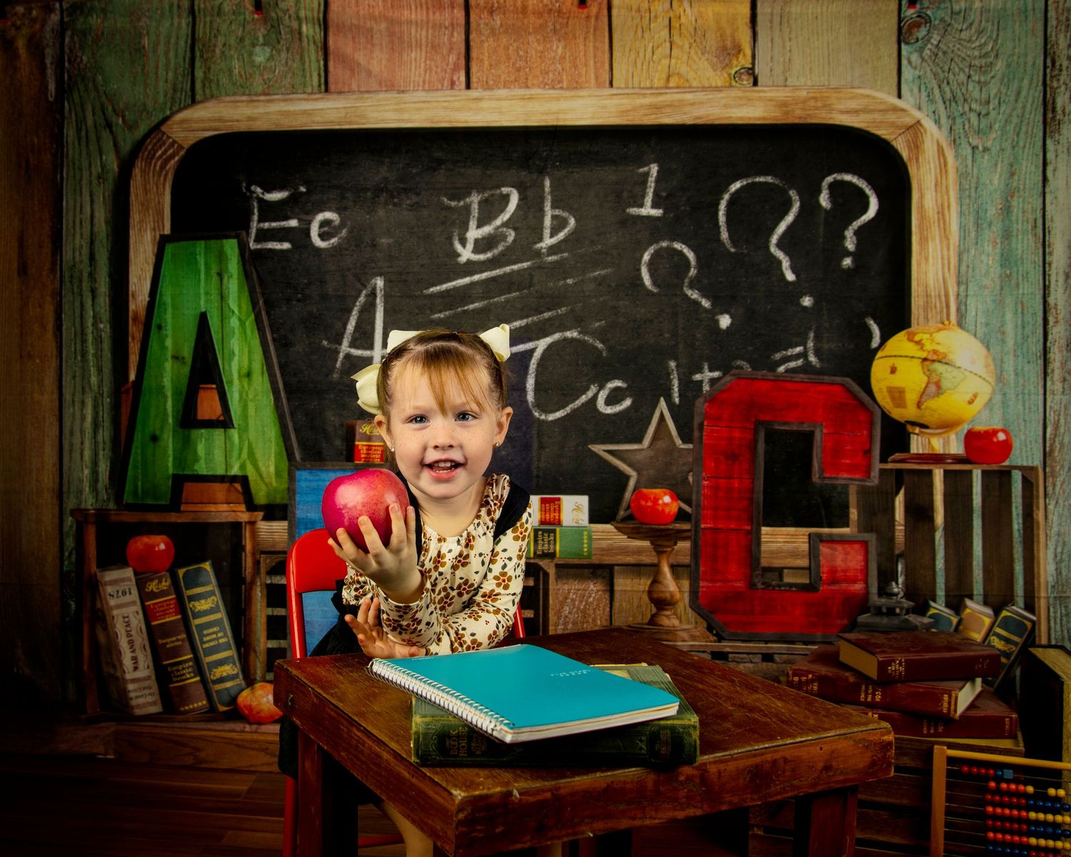 Educational scene with colorful ABC letters, a chalkboard, books, and a blue notebook on a wooden desk in vintage setting.