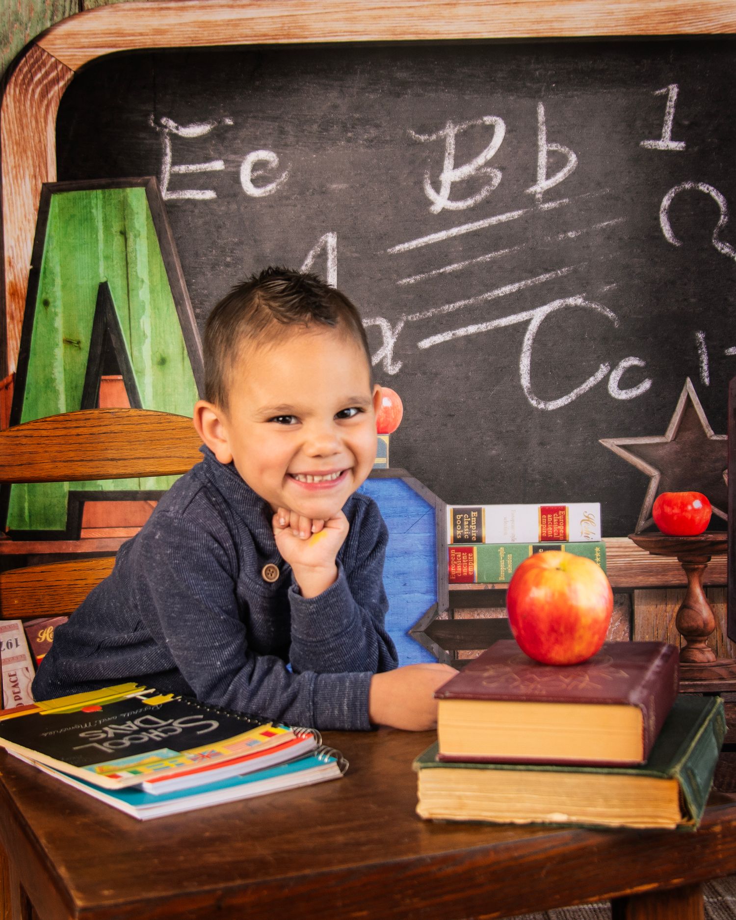School-themed photo with student, books, and alphabet letters on chalkboard.