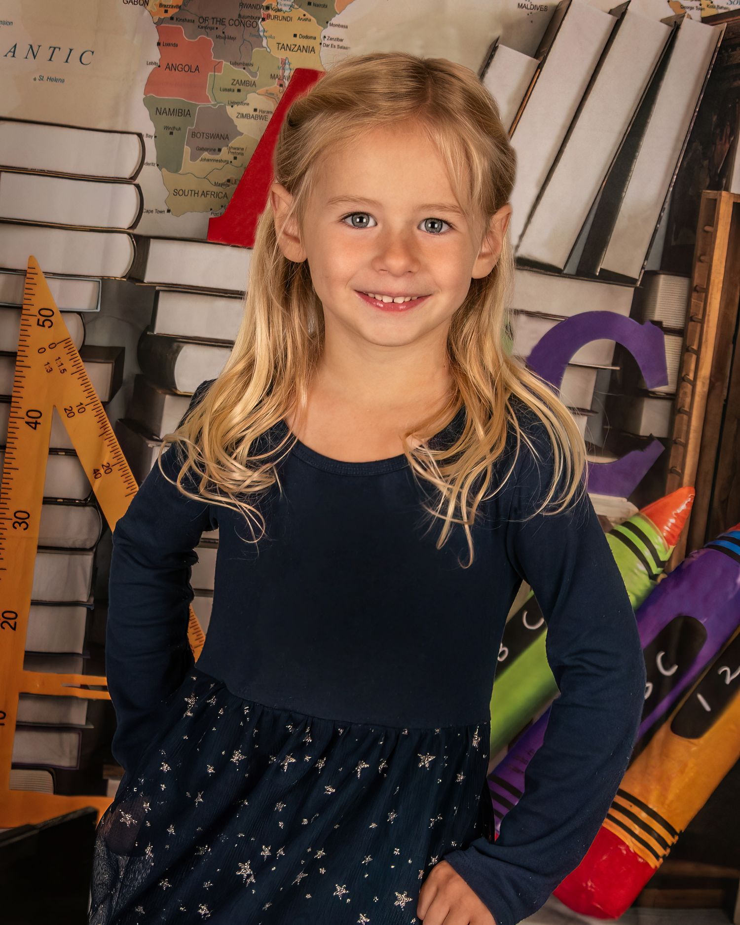 School portrait setting with stacked books, alphabet letters, and educational decorations.