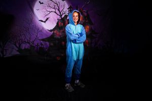 Silhouetted trees against purple night sky with full moon and flying bats create spooky Halloween atmosphere.