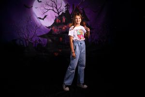 A spooky Halloween scene with silhouetted trees against a purple sky with bats and a full moon in the background.