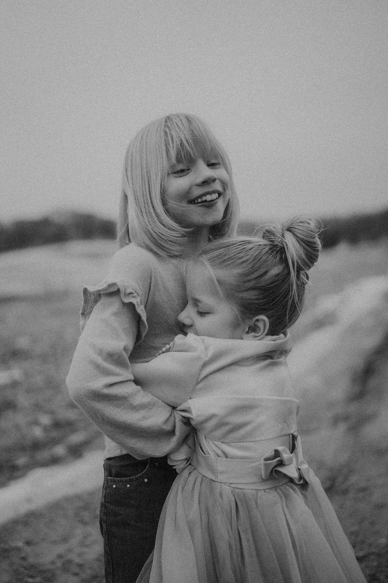 Wisconsin photographer capturing sisters in an open field hugging.