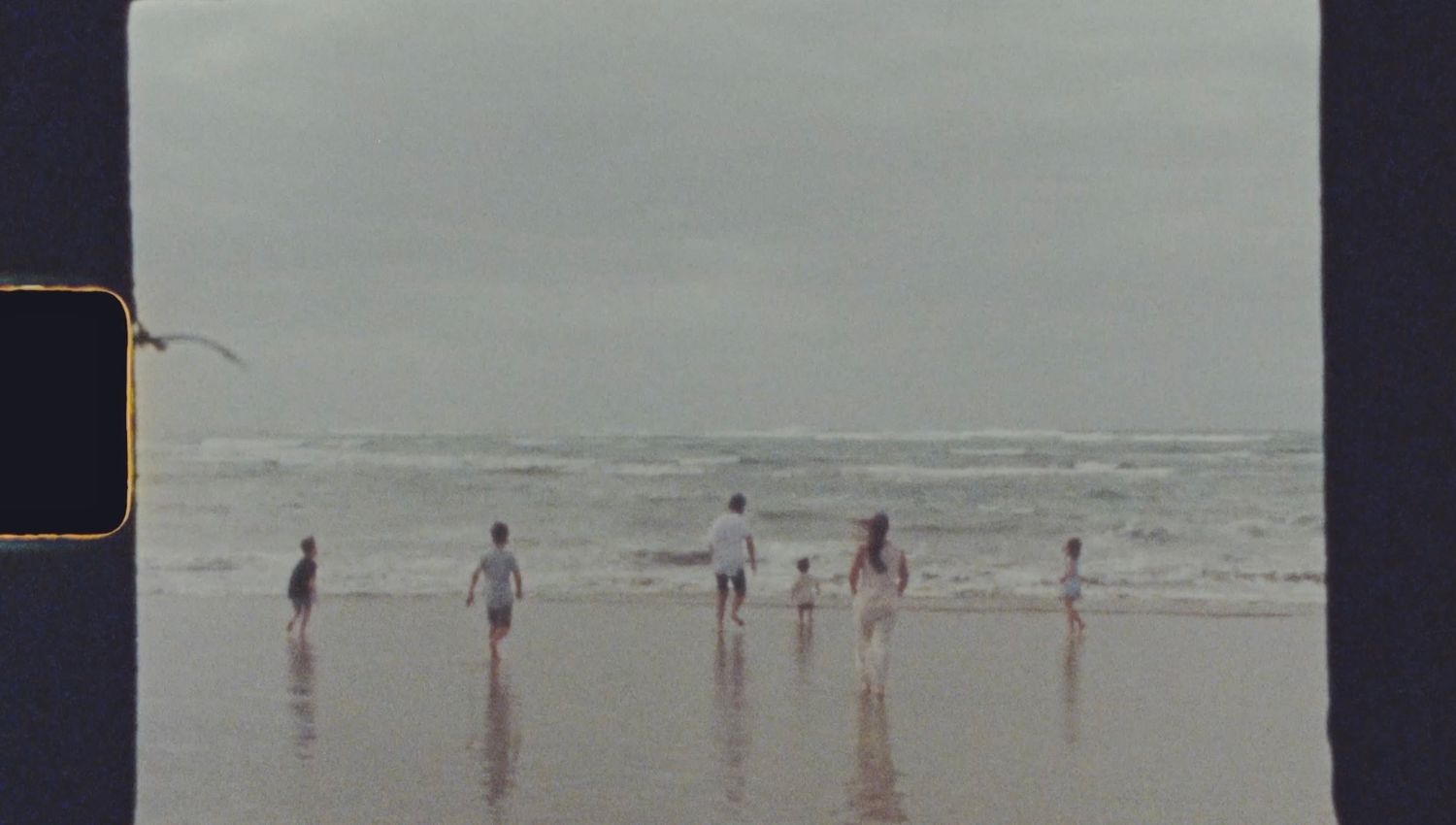still frame from super 8 of a family running in the shallow water at Ocean Grove beach