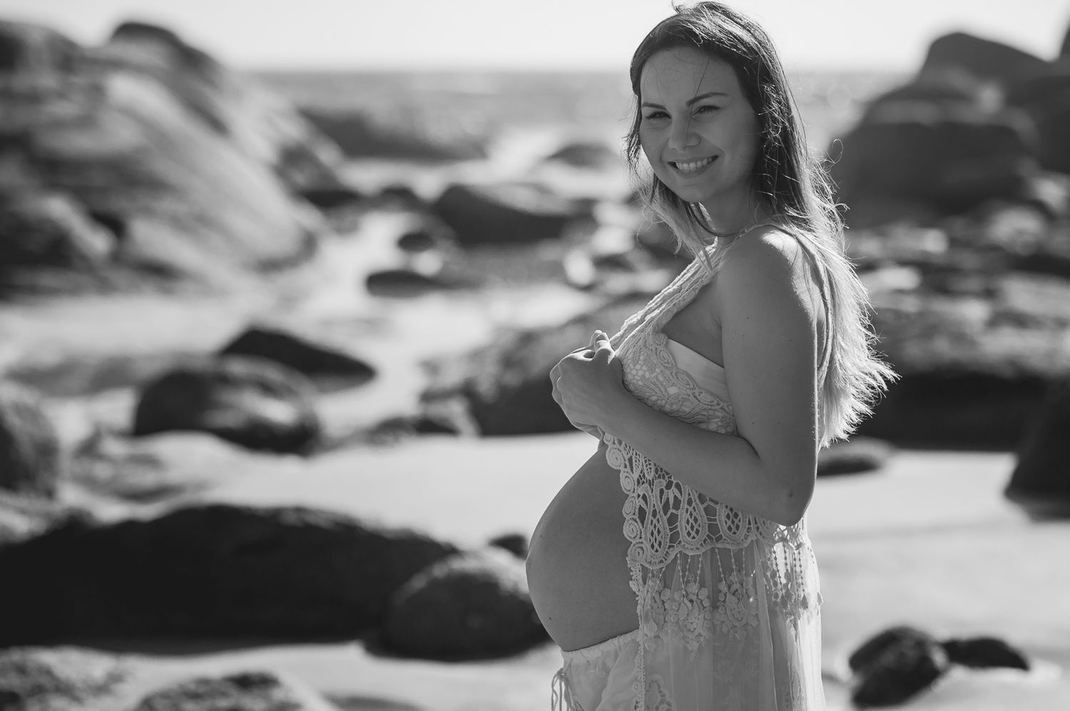A maternity photo session among rocky coastal formations in natural light.