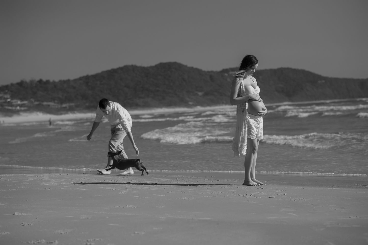 Two figures and a dog enjoy a peaceful moment on a windswept beach.