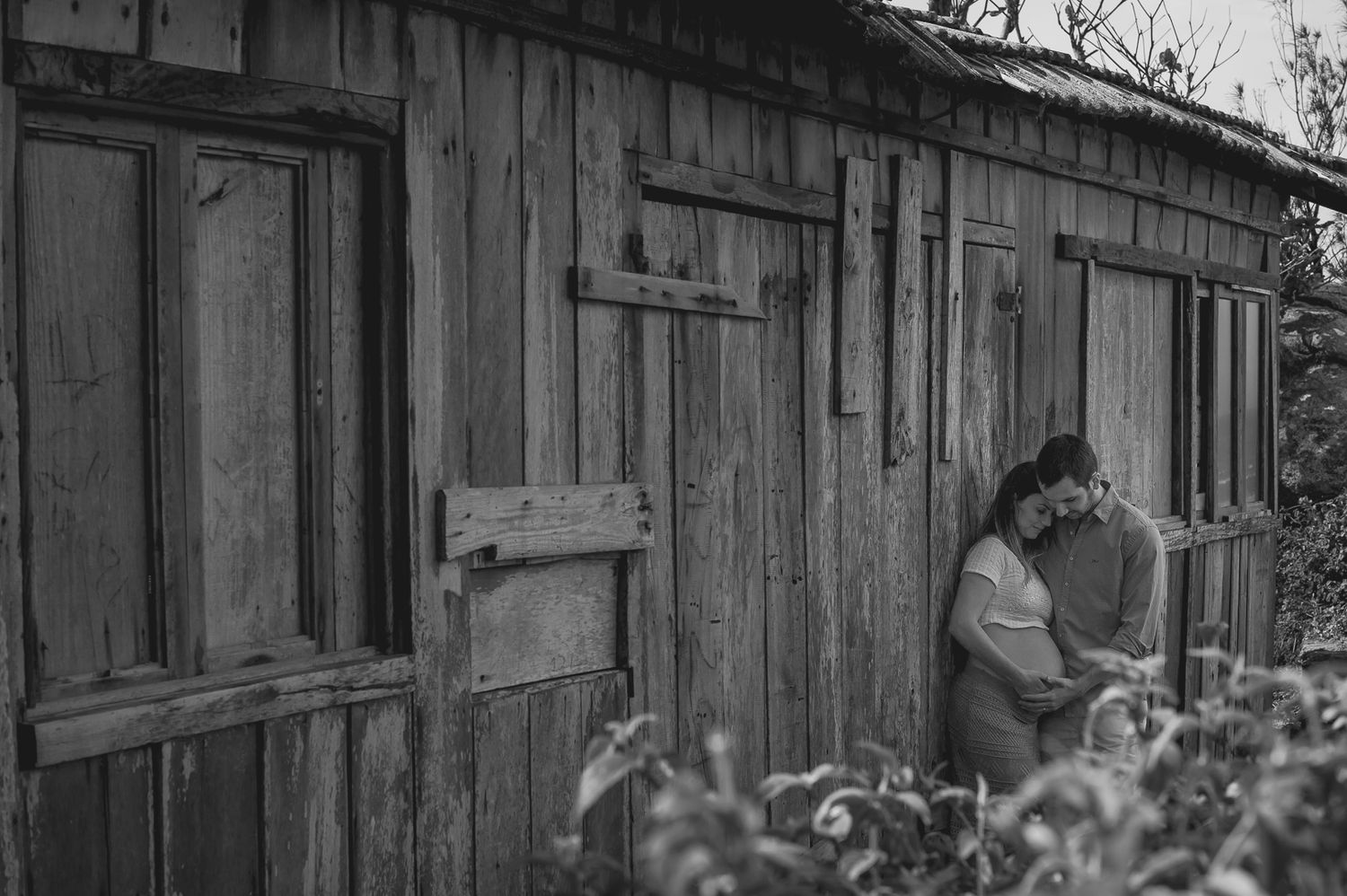Black and white photo of a rustic wooden cabin with figure in garden.