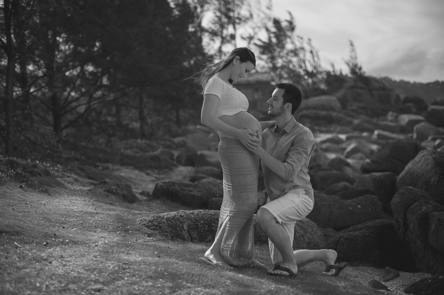 A black and white romantic moment captured among rocky coastal terrain.