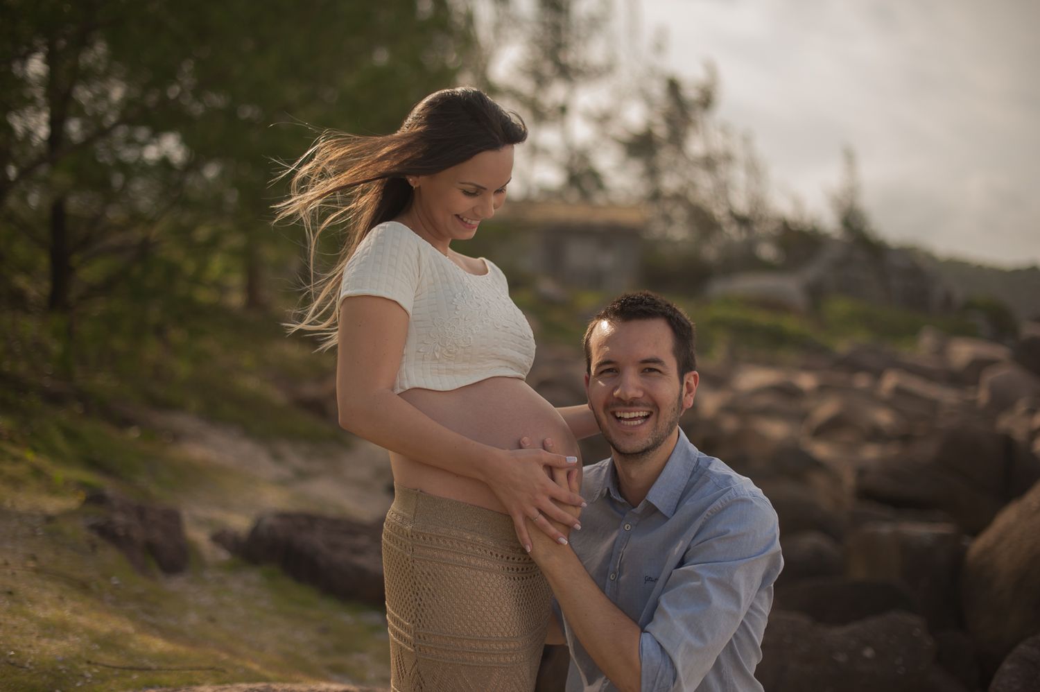 A couple shares an intimate moment outdoors as they celebrate an expected arrival.