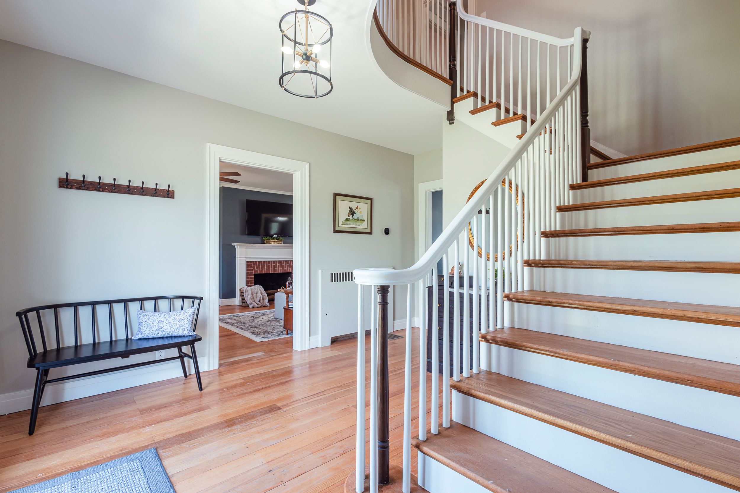 Modern staircase featuring wood treads and white risers with black metal balusters in bright interior.