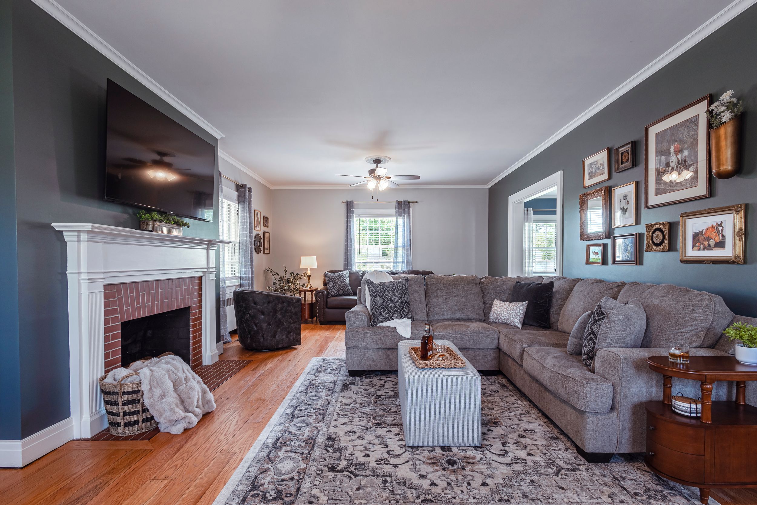 Spacious living room with gray walls, hardwood floors and comfortable seating arrangement.