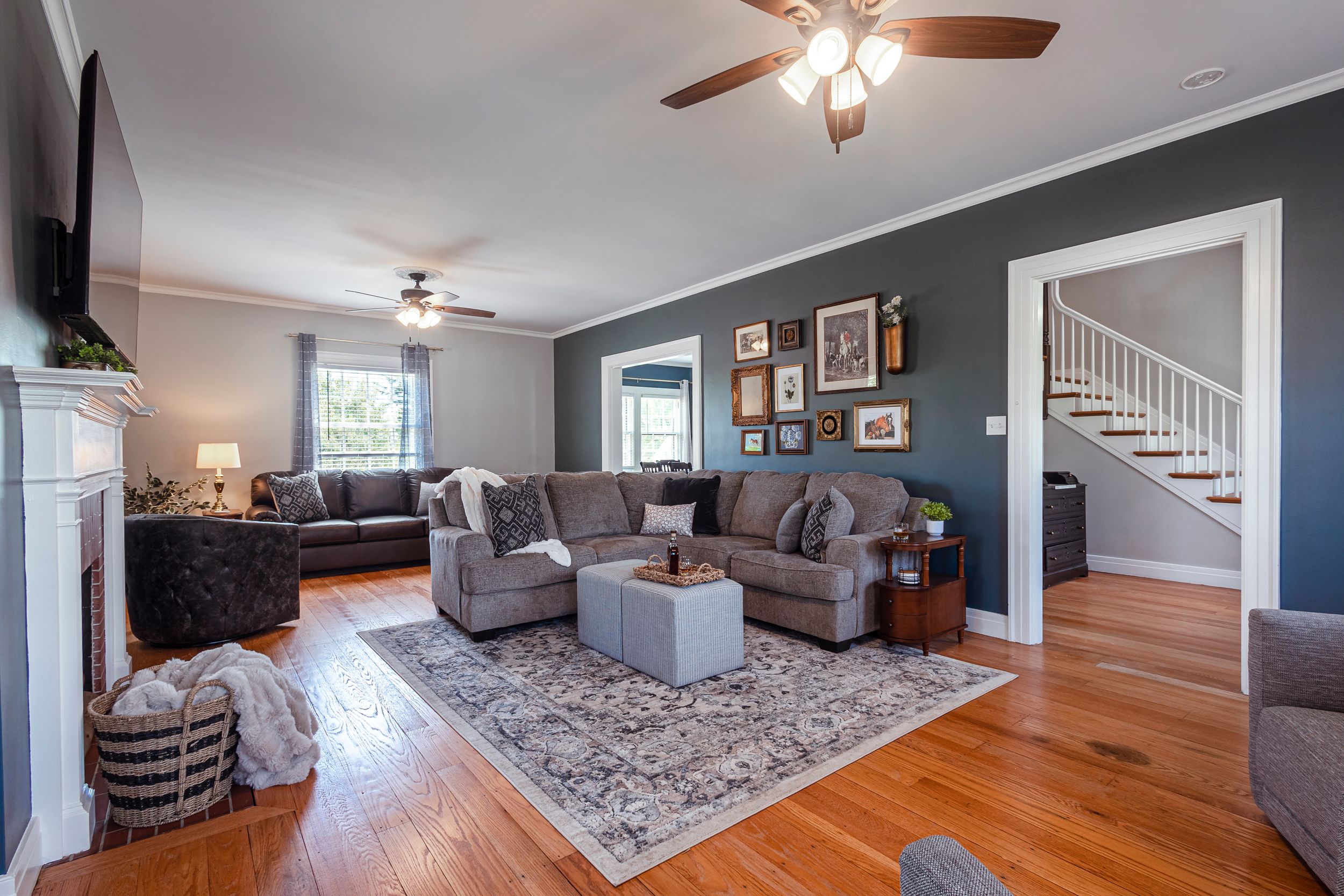 Open concept living space with dark accent walls, hardwood floors and contemporary furnishings.