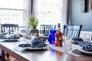Formal dining table set with blue polka dot napkins, wine glasses, and decorative blue glass bottles.