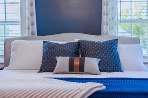 Close-up of bed with textured blue and white pillows and cozy knit throw blanket.