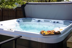 Modern hot tub with clear blue water positioned next to outdoor furniture on a stone patio.
