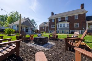 Outdoor patio area with Adirondack chairs around a fire pit and mulched landscaping.