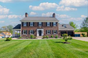 Traditional brick colonial home with white trim and symmetrical design on a manicured lawn.