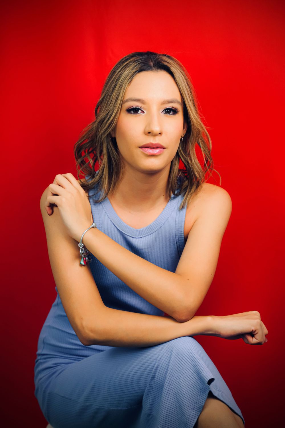 Portrait session featuring blue ribbed dress against vivid red background.