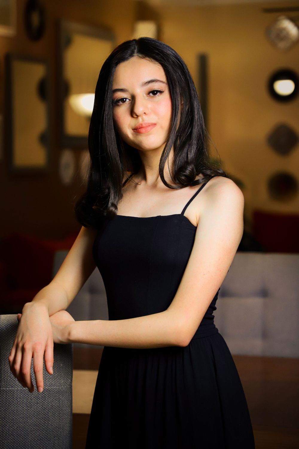 Studio portrait in black dress with moody lighting and warm tones.