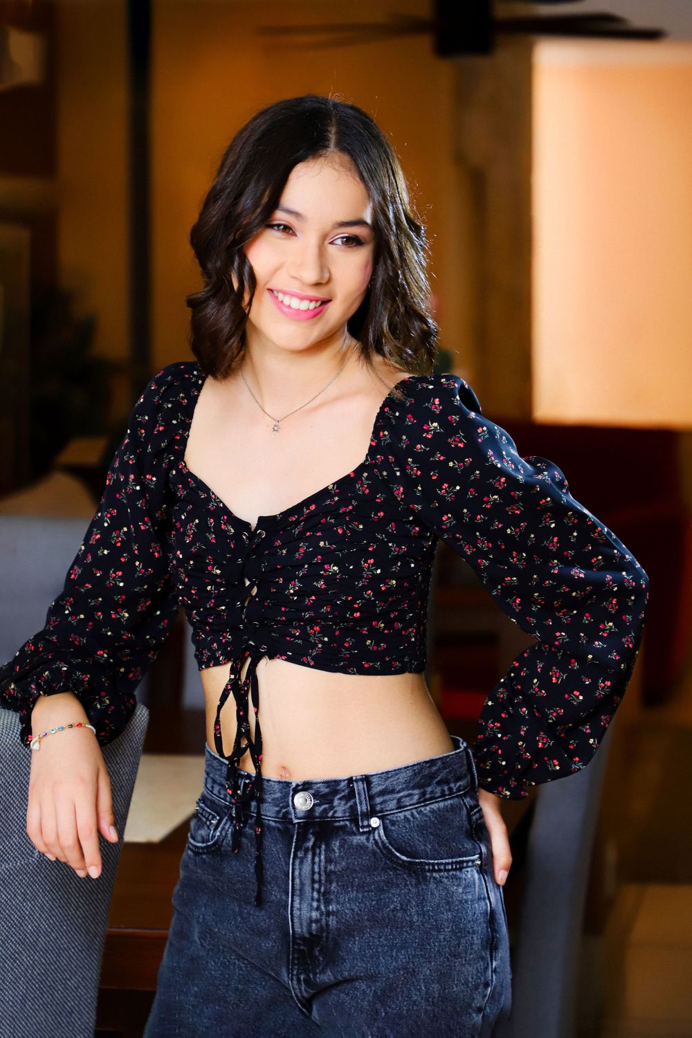 Stylish portrait showing crop top with floral print and high-waisted jeans in indoor setting.