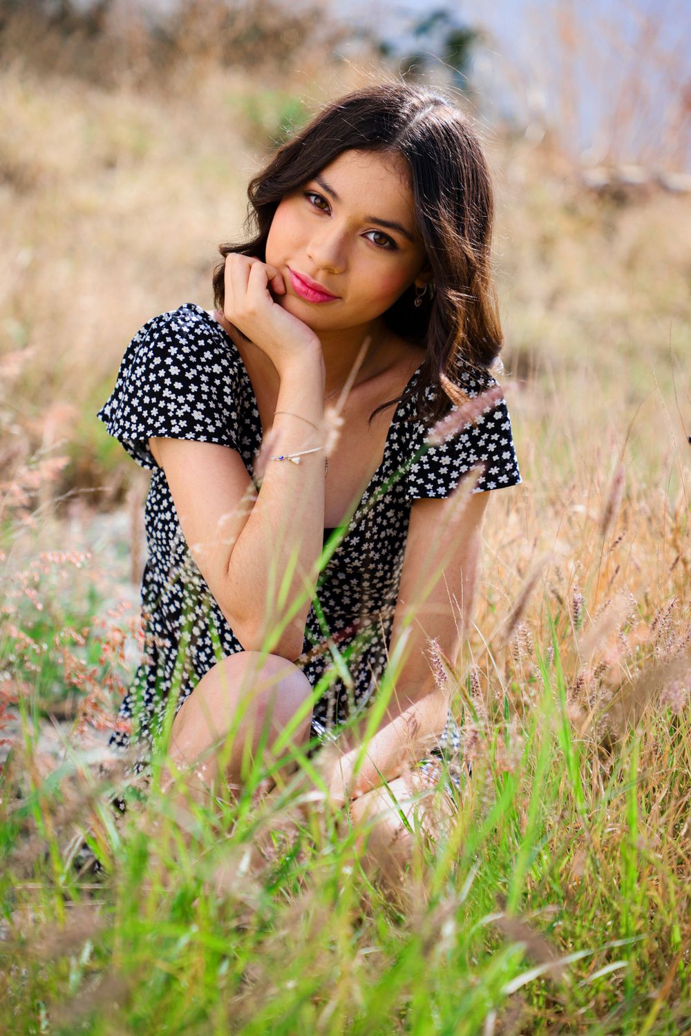 Portrait in polka dot dress laying in wildflower field during golden hour.