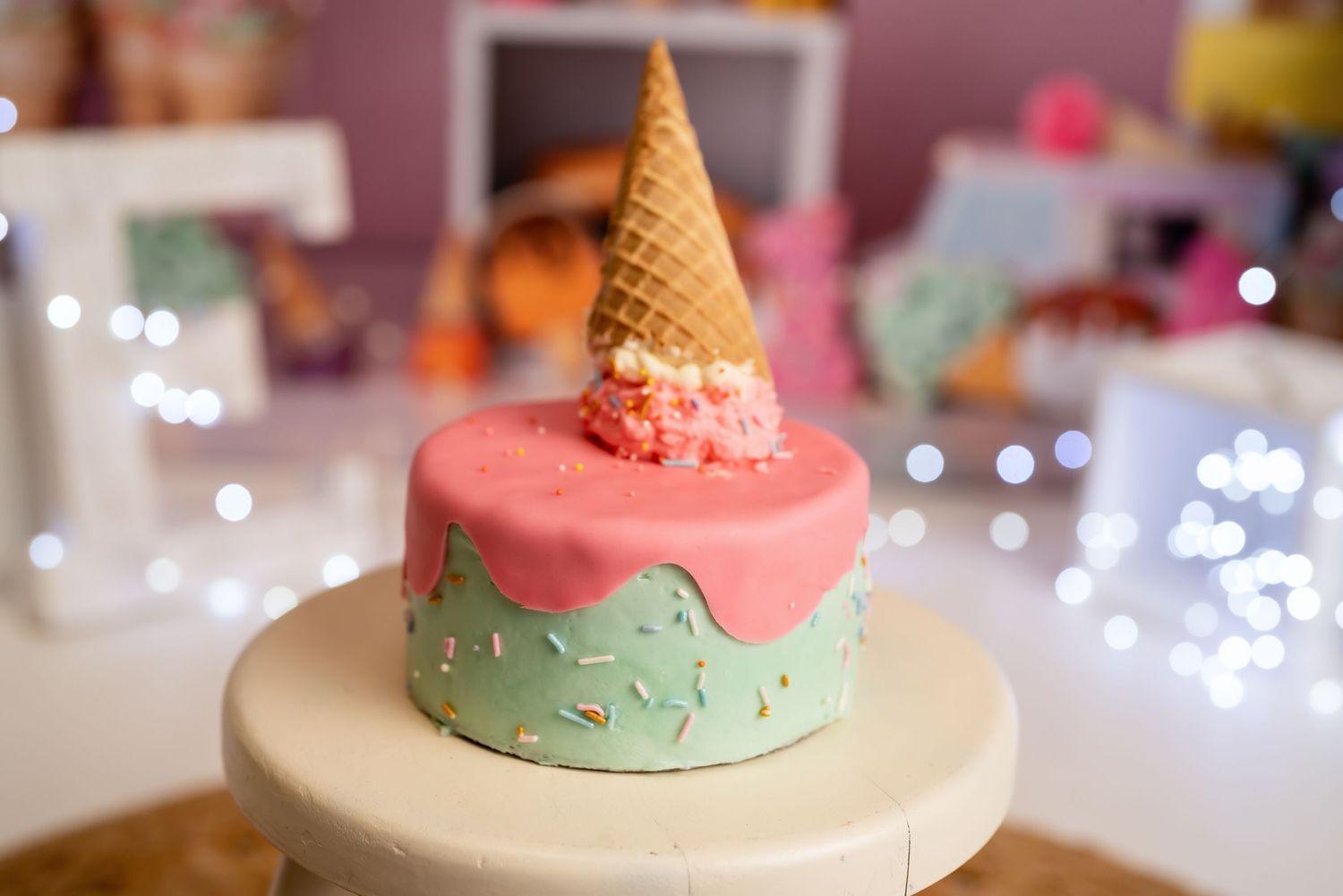 Ice cream cone themed cake with pink and mint frosting for first birthday party.