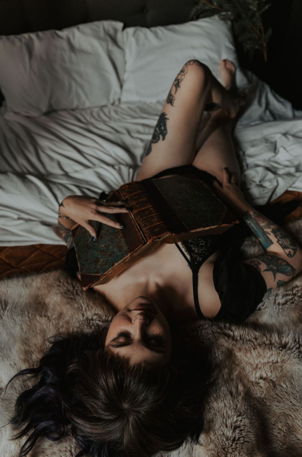 Artistic boudoir photograph with vintage book and dark moody lighting.