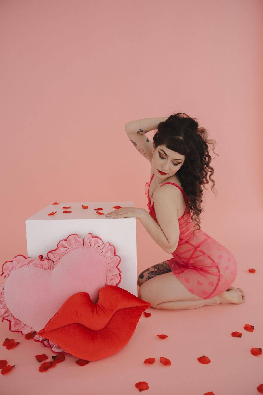 Valentine's day themed photo with red and pink heart decorations and rose petals on pink background.
