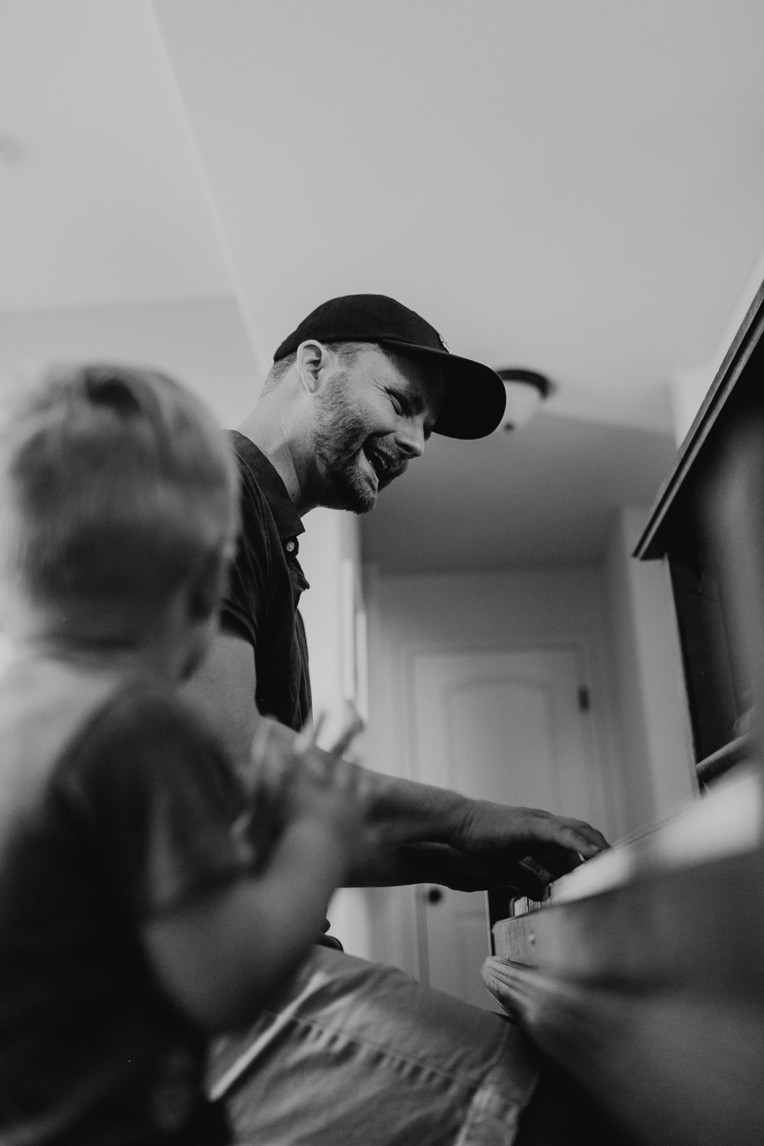 Intimate black and white moment of playing piano together in home setting.