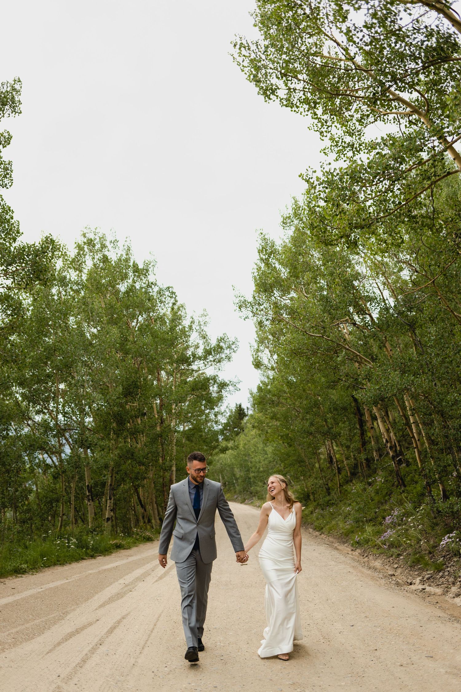 bride and groom walking through aspens