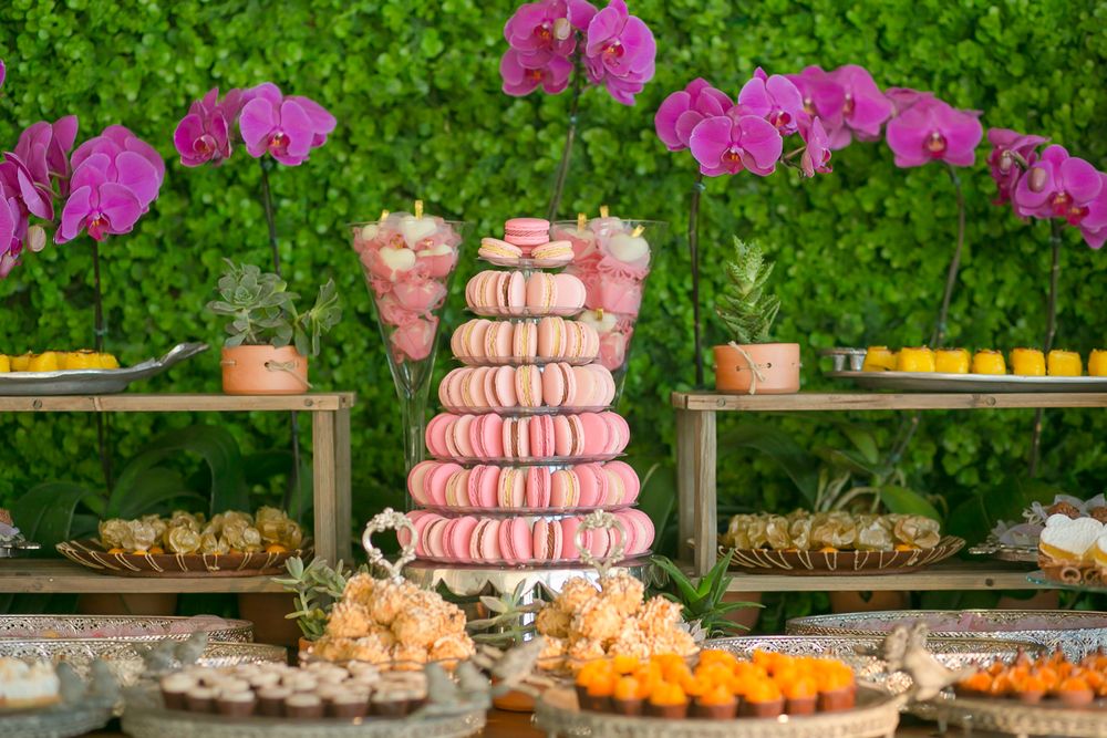Pink macaron tower with dessert table display featuring fresh orchids and citrus fruits.