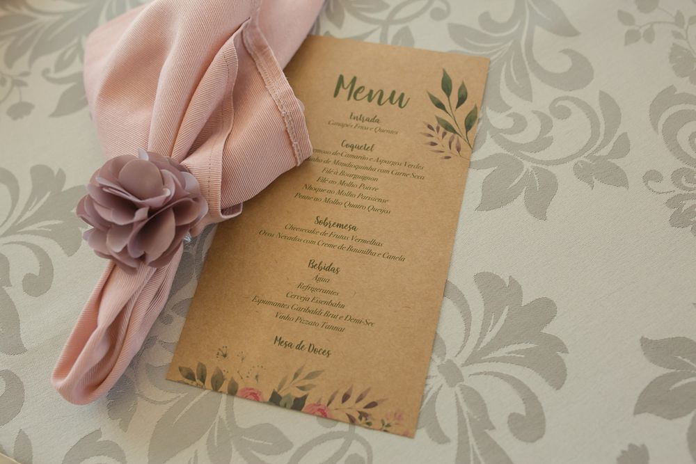 Wedding menu card with floral design paired with pink napkin and flower accent.