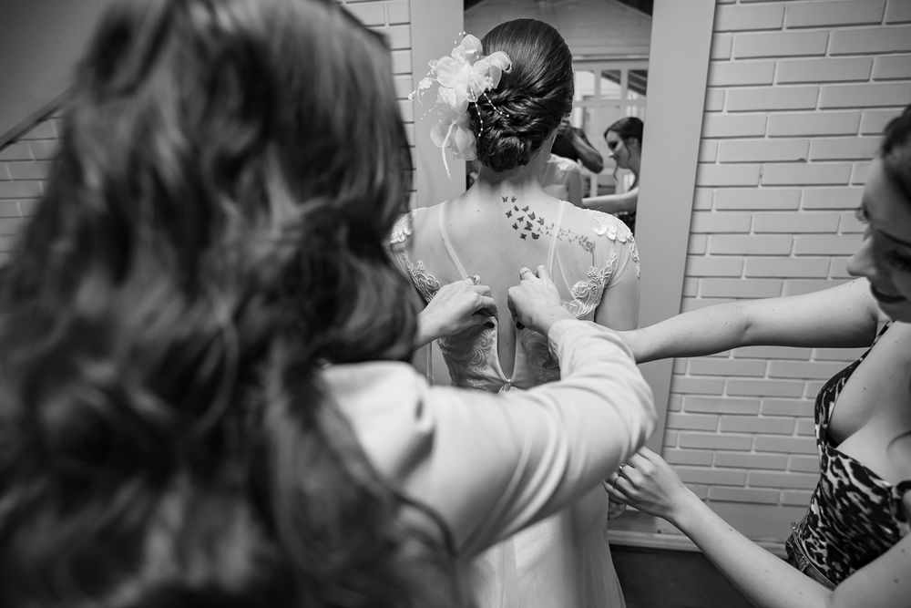 Behind the scenes moment of wedding dress preparations with helpers.