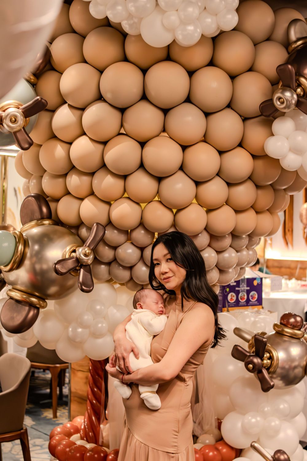 Elegant baby celebration with brown and white balloon arch decorations.