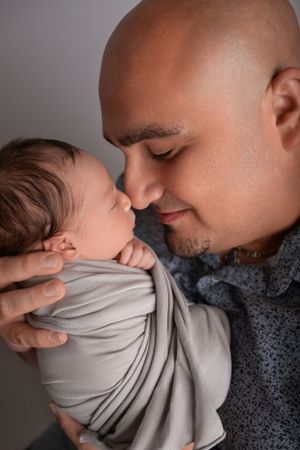 An intimate close-up of parent and newborn sharing a tender nose-to-nose moment.