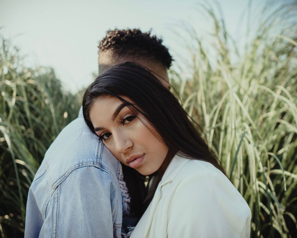 A romantic outdoor portrait of a couple against tall grass at sunset.
