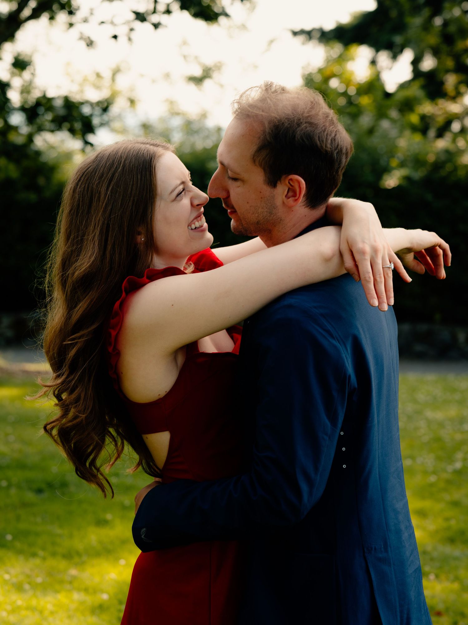 Two people sitting close together on a blanket in a sunny field with bokeh lights.