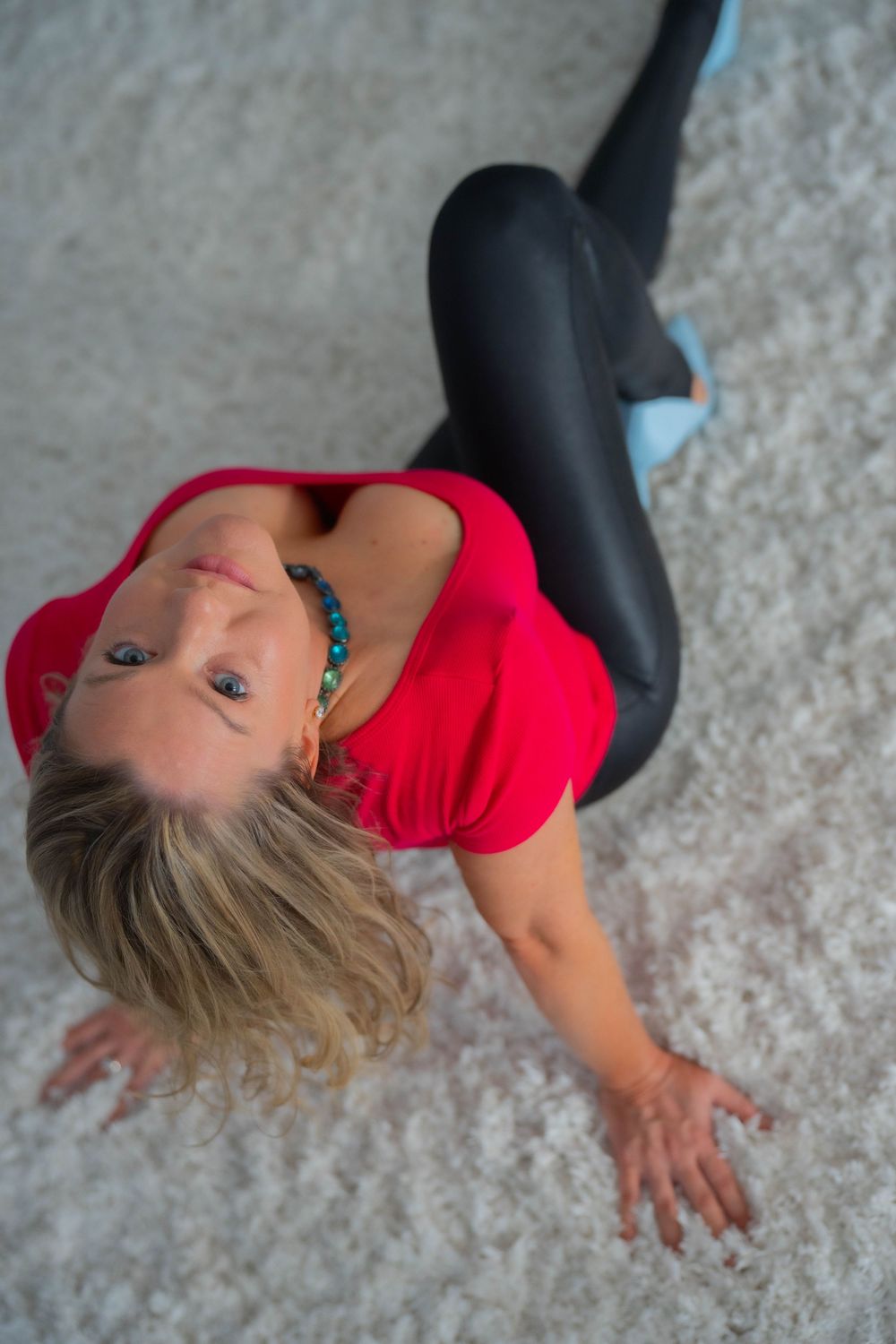Person in red top lying on white carpet making dynamic pose.