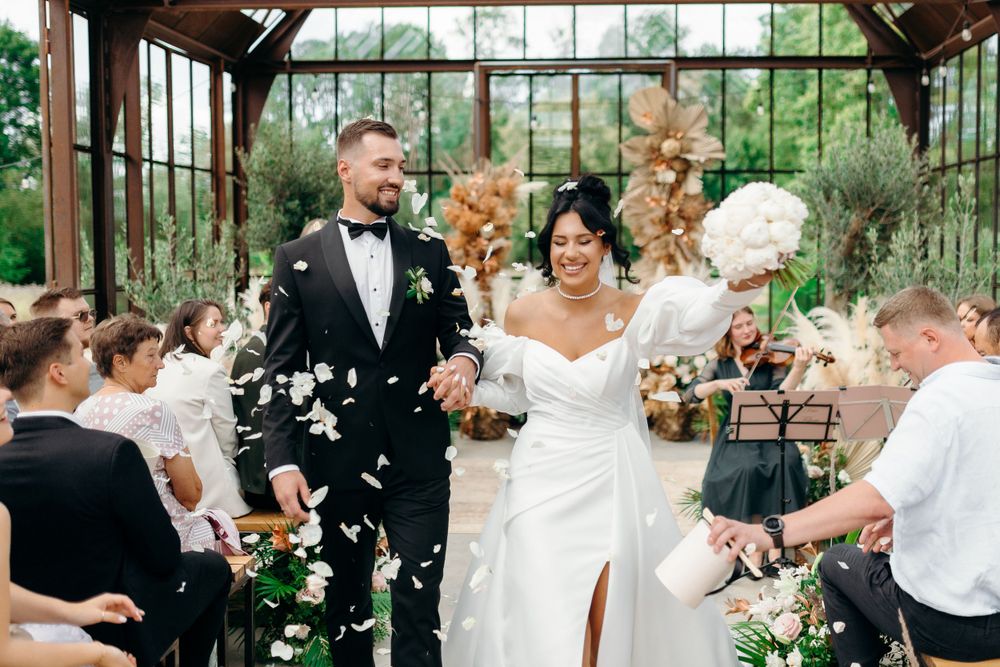 Wedding celebration in greenhouse venue with elegant floral decorations.