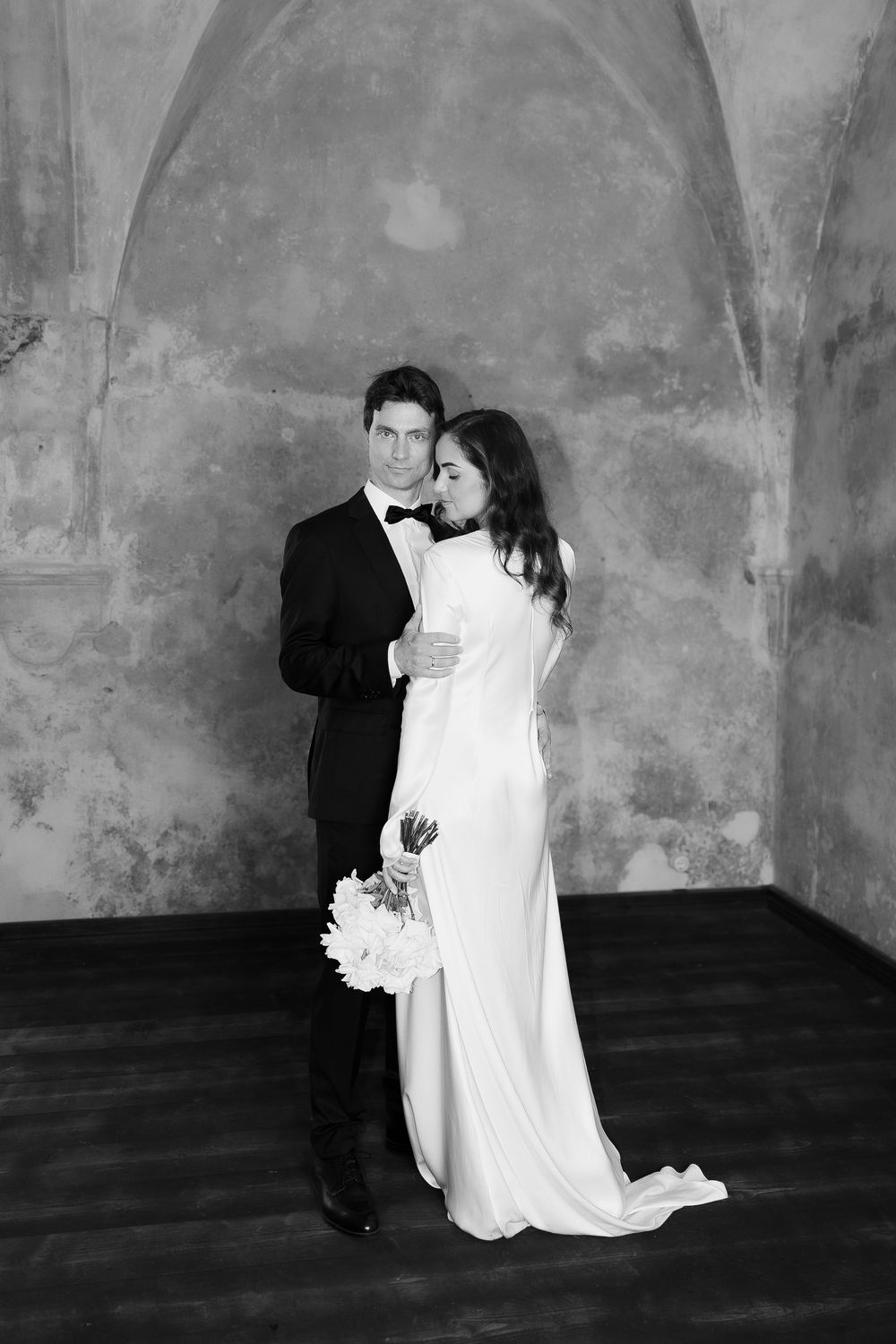 Artistic black and white wedding portraits against textured wall.
